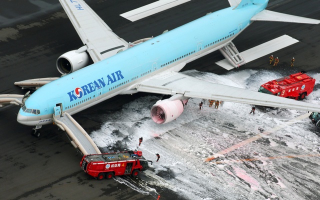 An+aerial+picture+shows+firefighters+spraying+foam+at+the+engine+of+a+Korean+Air+Lines+plane